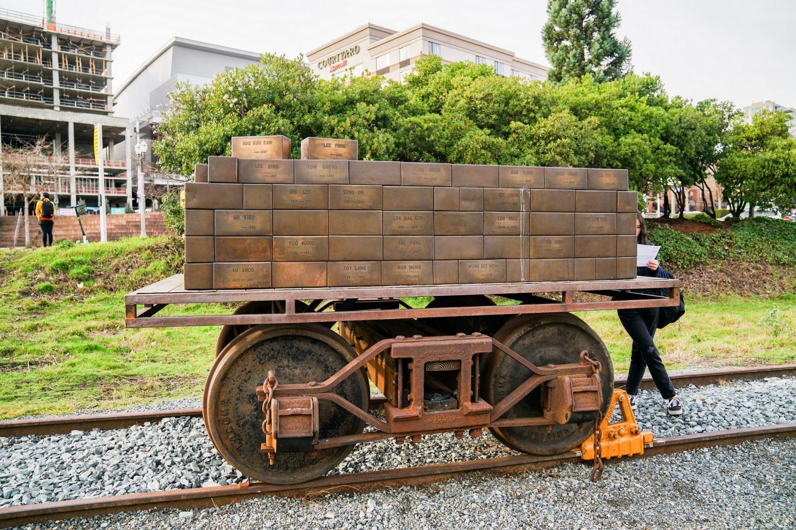 A photo of a bronze sculpture called Shipment to China. The sculpture includes roughly a hundred small bronze boxes on top of an antique train truck.