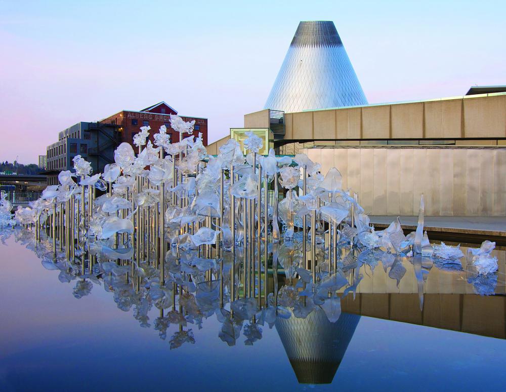 Entrance to Museum of glass, showing image of Fluent Steps, a glass art piece by Martin Blank, of several glass disks suspended over a reflecting pool. 
